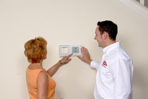 Technician and Homeowner Looking at New Thermostat